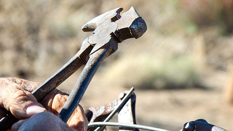 Close-up of a pair of fencing pliers in someone's hand
