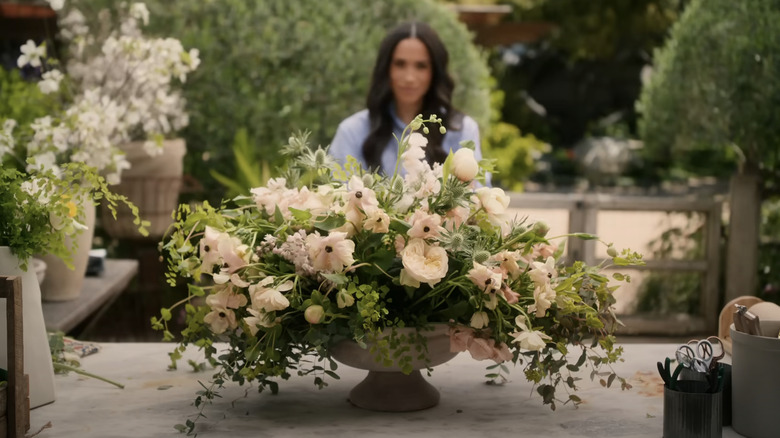 A peach-colored flower arrangement sits on a table in front of Meghan, the Duchess of Sussex