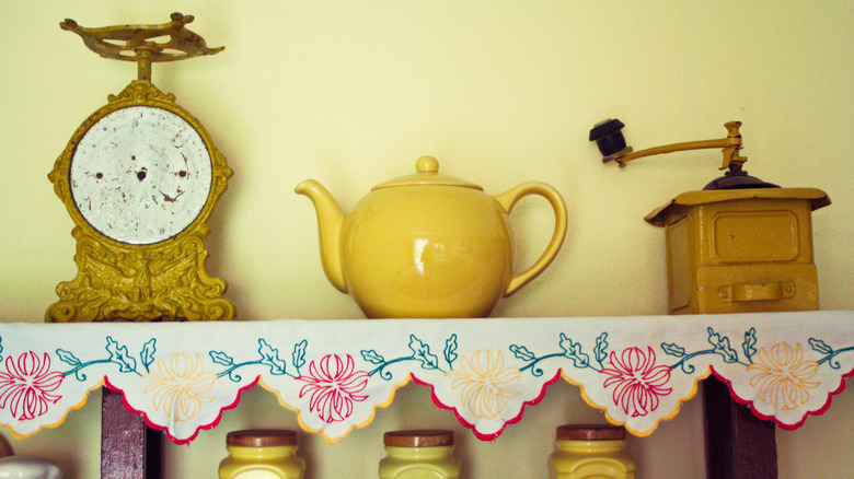 Kitchen shelf adorned with various vintage pieces, including a teapot, flour sister, and jars