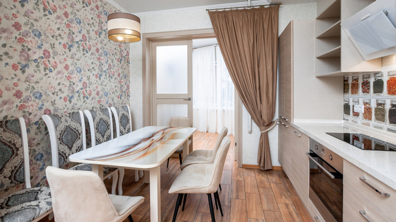 Blue, purple, and pink floral patterned wallpaper adorning a wall in a small kitchen and dining room