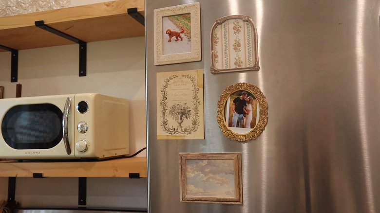 A small magnet gallery wall with photos and prints on a stainless still refrigerator