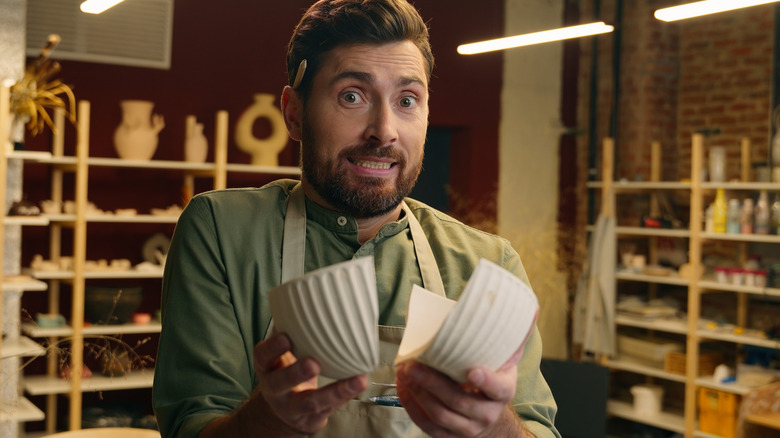 Man holding a broken white ceramic bowl