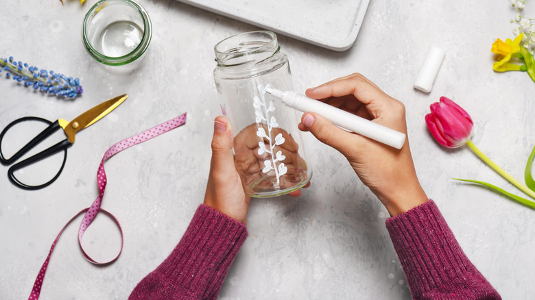 Woman decorating glass jar with marker