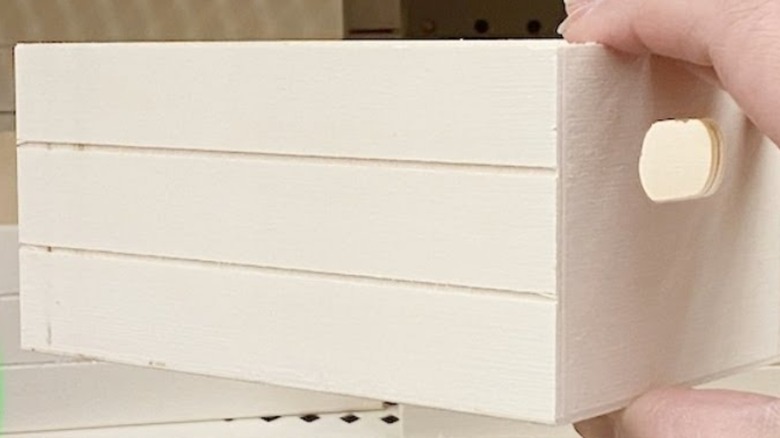 A person selecting a mini wooden crate from Dollar Tree
