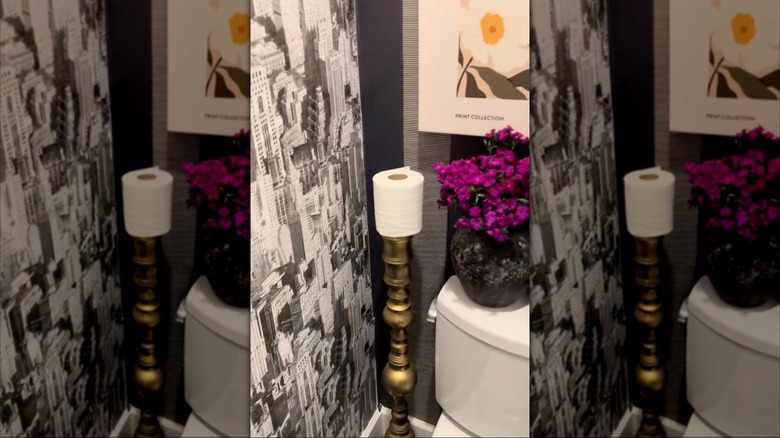 Candle stand turned into toilet paper holder in bathroom.