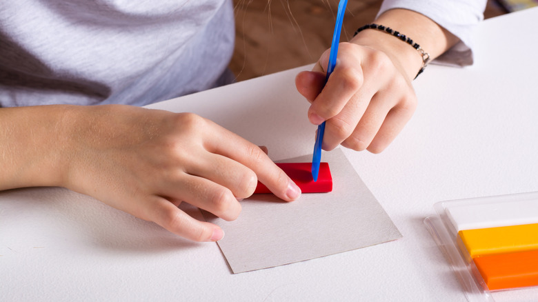person cutting into red polymer clay
