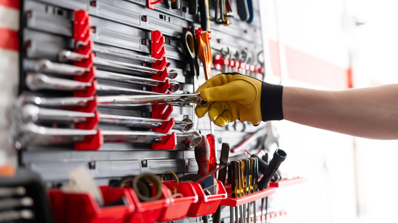 A person grabbing a wrench from their tool kit