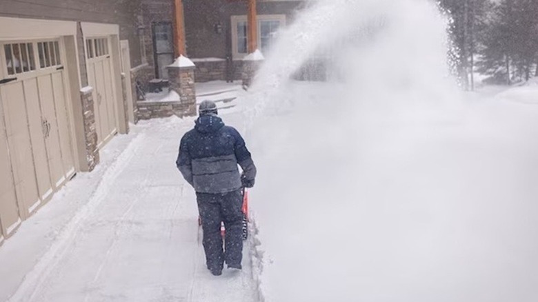 Person throwing snow in front of a garage