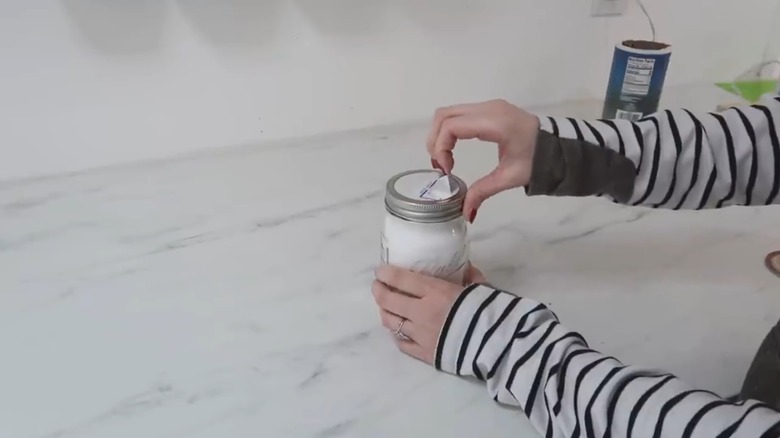 Woman opening spout on a DIY sugar shaker made from a Mason jar