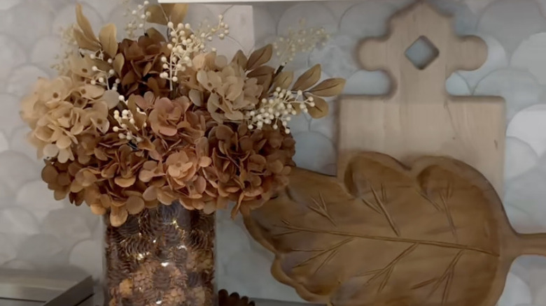 Thanksgiving centerpiece on a counter next to a leaf bowl and cutting board