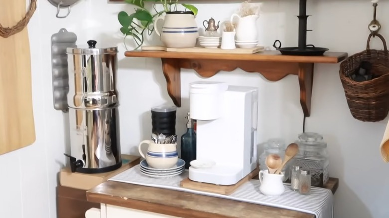 Thrifted coffee bar with a water filter, coffee maker, milk frother, cups, and more