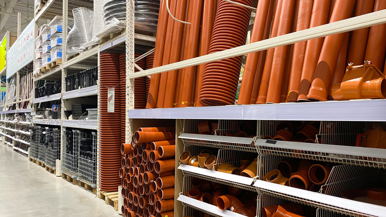 Orange PVC pipes in various dimensions on the shelves of a hardware store.