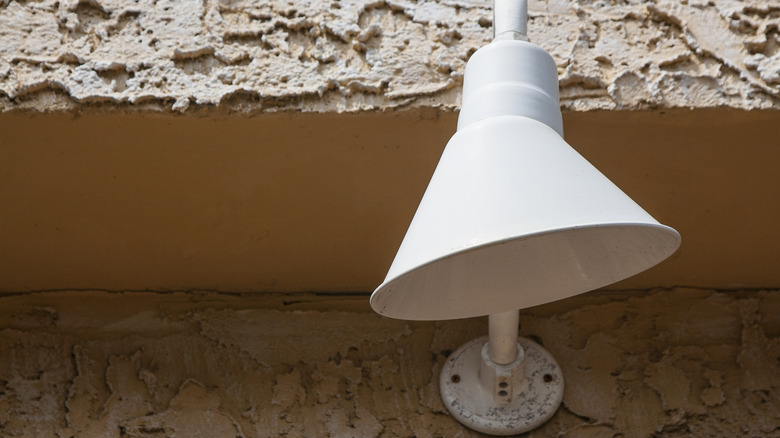 White shielded light attached to roughly textured outside wall