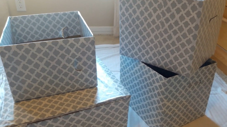 A cardboard box covered in woodgrain contact paper and lined with turquoise and white patterned contact paper