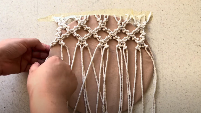 person doing macramé on a lid