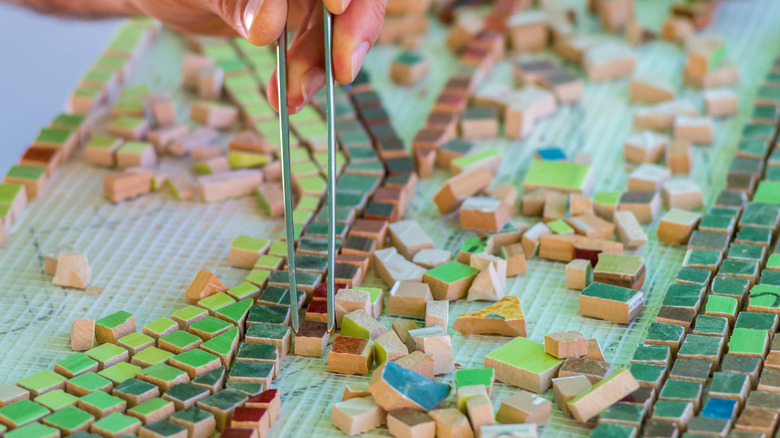 someone carefully placing tile into mosaic design