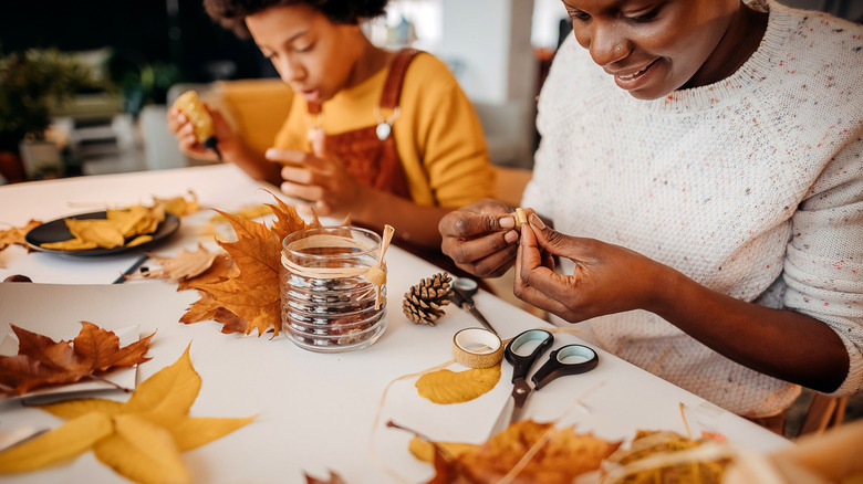 An African American mother and child work together on a fall craft project.
