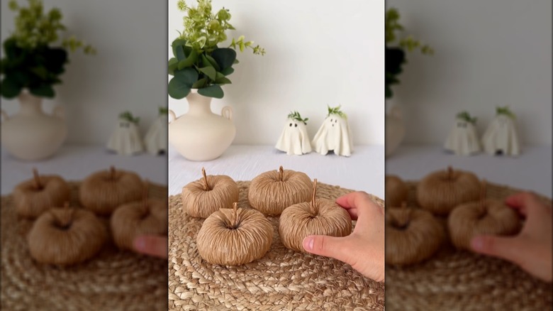 A hand touches a paper pumpkin that's part of a trio on display.