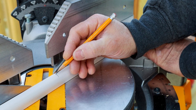 person marking cut point on quarter round on miter saw