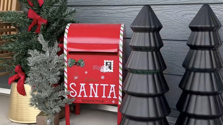 Holiday porch decor with two Dollar Tree black-painted trees, a red faux mailbox, and trees with bows