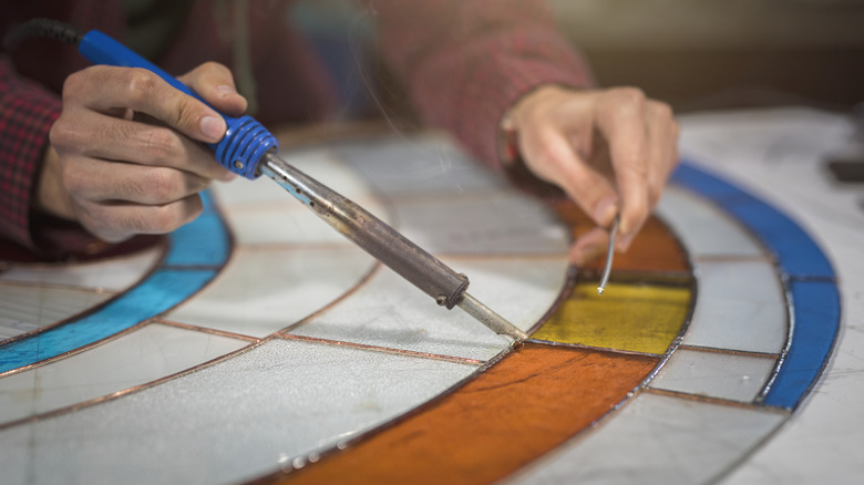 A person works on a real stained glass window