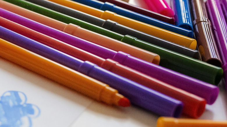 Markers in assorted colors laying on a surface
