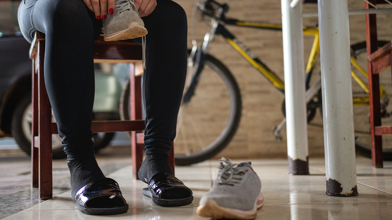 A person sits on a chair in a garage while they put their shoes on.