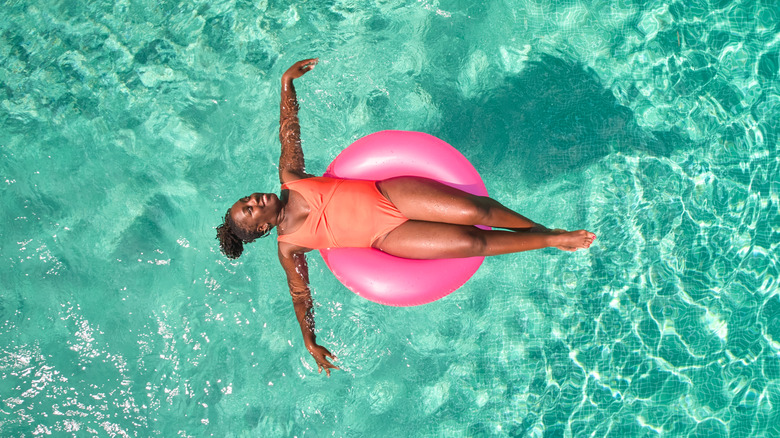 A woman enjoying a pool and laying on a floatie