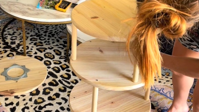 Person building a DIY spinning shoe rack from wood boards and dowel rods