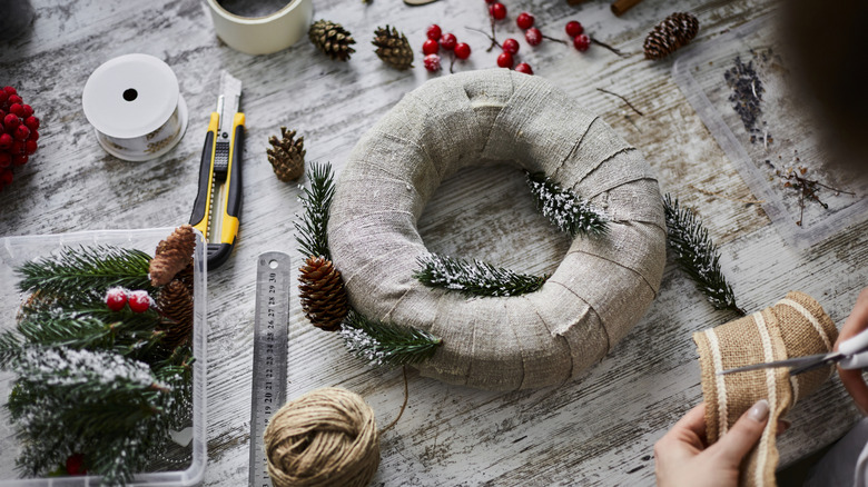 A person decorates a burlap wreath for winter