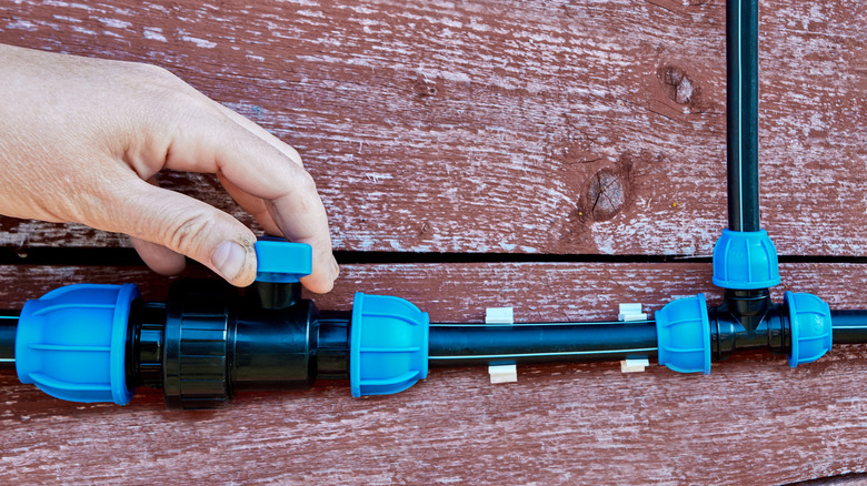 Hand turning the shut-off valve of a water supply pipe