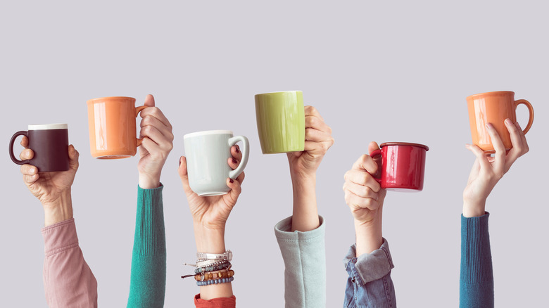 hands holding colorful mugs
