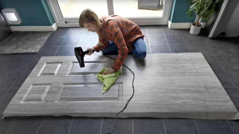 person blowdrying vinyl door covering