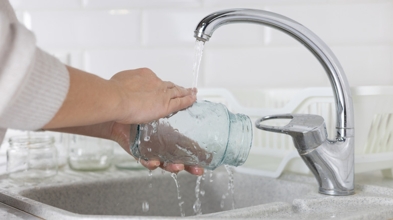Hands rinsing and empty jar under the faucet