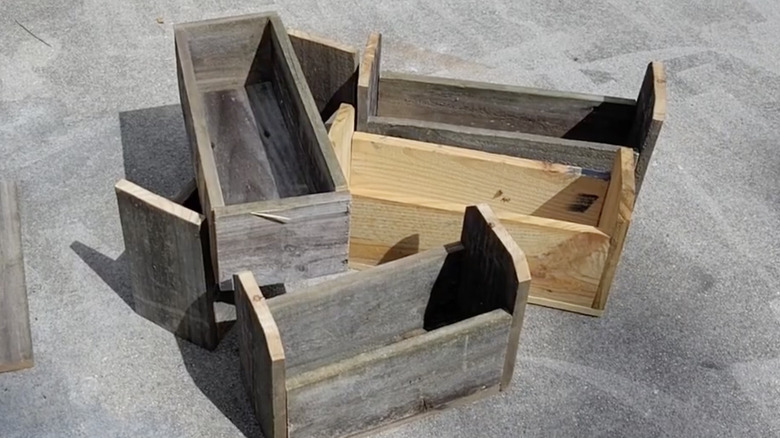 Four small wooden garden boxes on concrete.