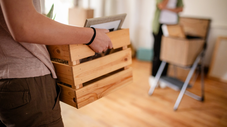 A women carrying a wooden crate into a room