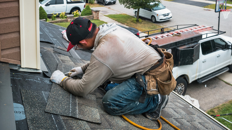 Roofer installing new shingles on a house