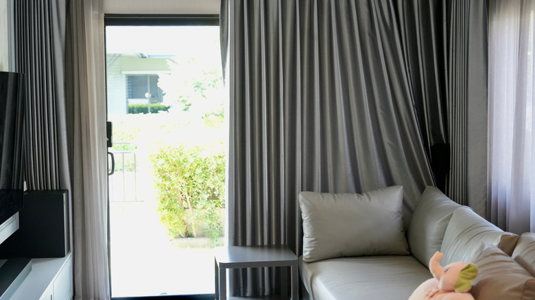 sliding glass door with large gray curtains in small living room