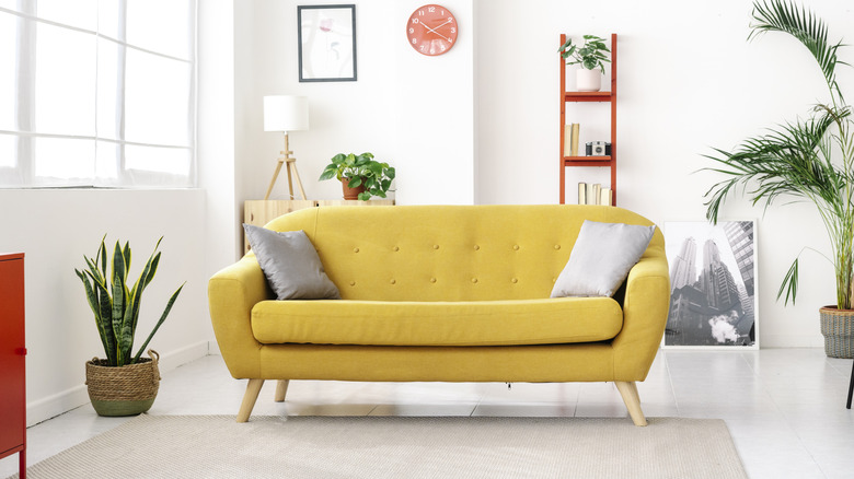 Interior view of a modern living room, featuring a custom yellow couch, potted plants, and other design elements.