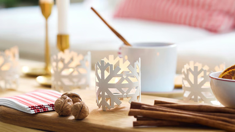 Several snowflake candle holders from IKEA with candles inside sitting on a table next to holiday items