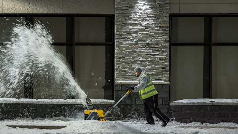 A man uses the Dewalt electric snow blower to clear a path.