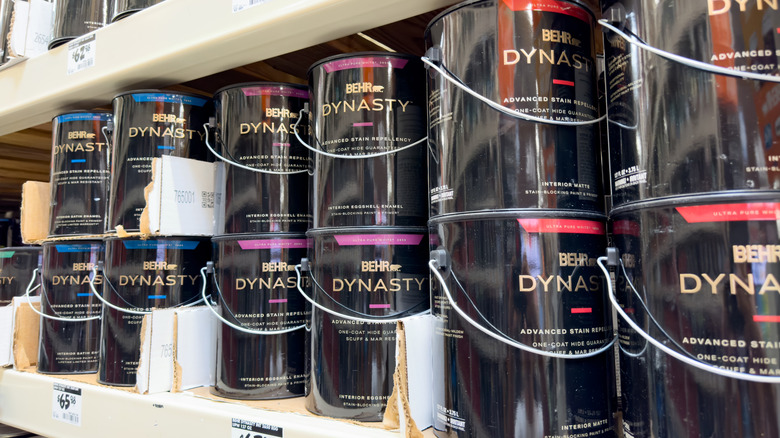 A series of Behr Dynasty paint cans in different colors on a shelf in Home Depot