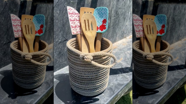 Handmade lariat rope utensil holder with wooden spoons and spatulas inside.
