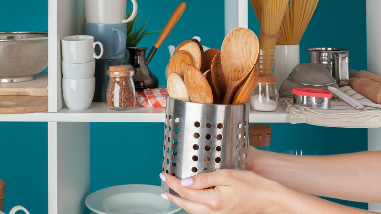 Woman holding old canister used as a utensil holder.