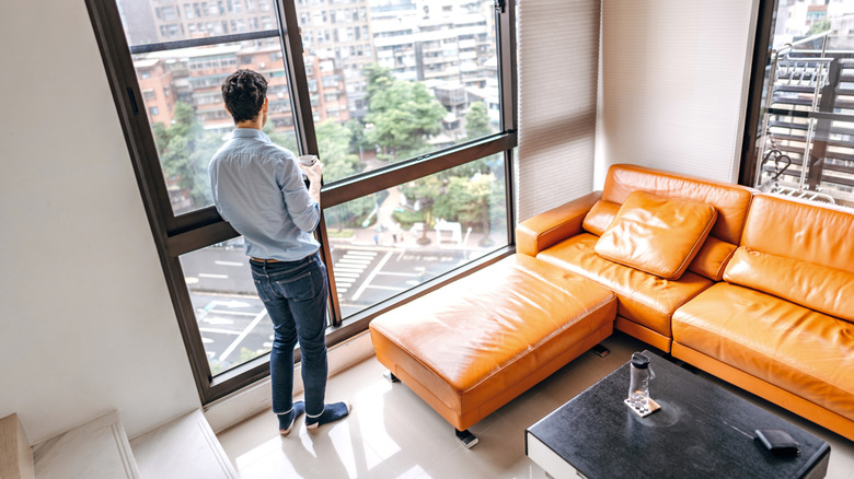 Man looking out the window of a living room