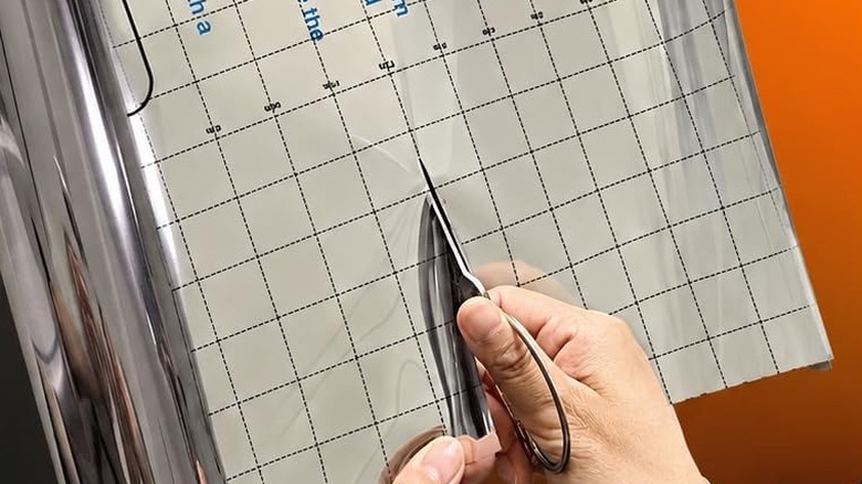 Person cutting a roll of window film with scissors