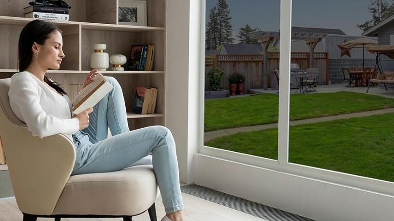 Woman reading a book and sitting near a window with film on it
