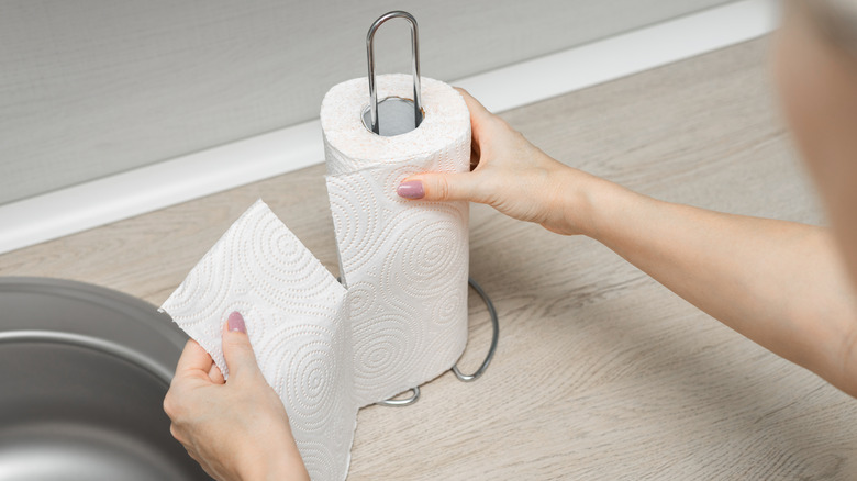 Woman tearing paper towel from paper towel holder.