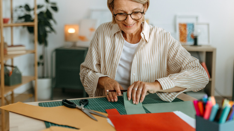 Woman smiling while crafting with colorful paper.