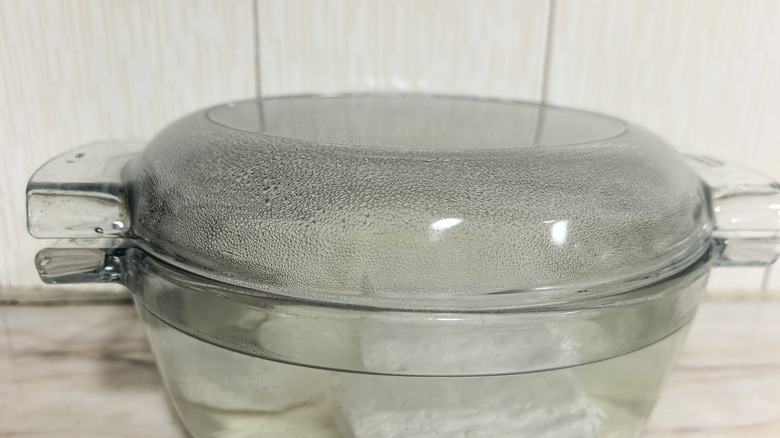 An empty transparent glass casserole dish sits on the countertop in a kitchen.